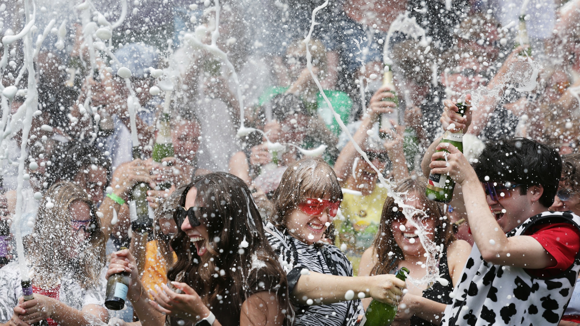 students spray bottles of champagne in celebration