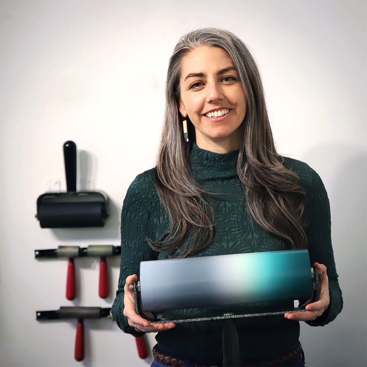 Smiling woman surrounded by printmaking tools