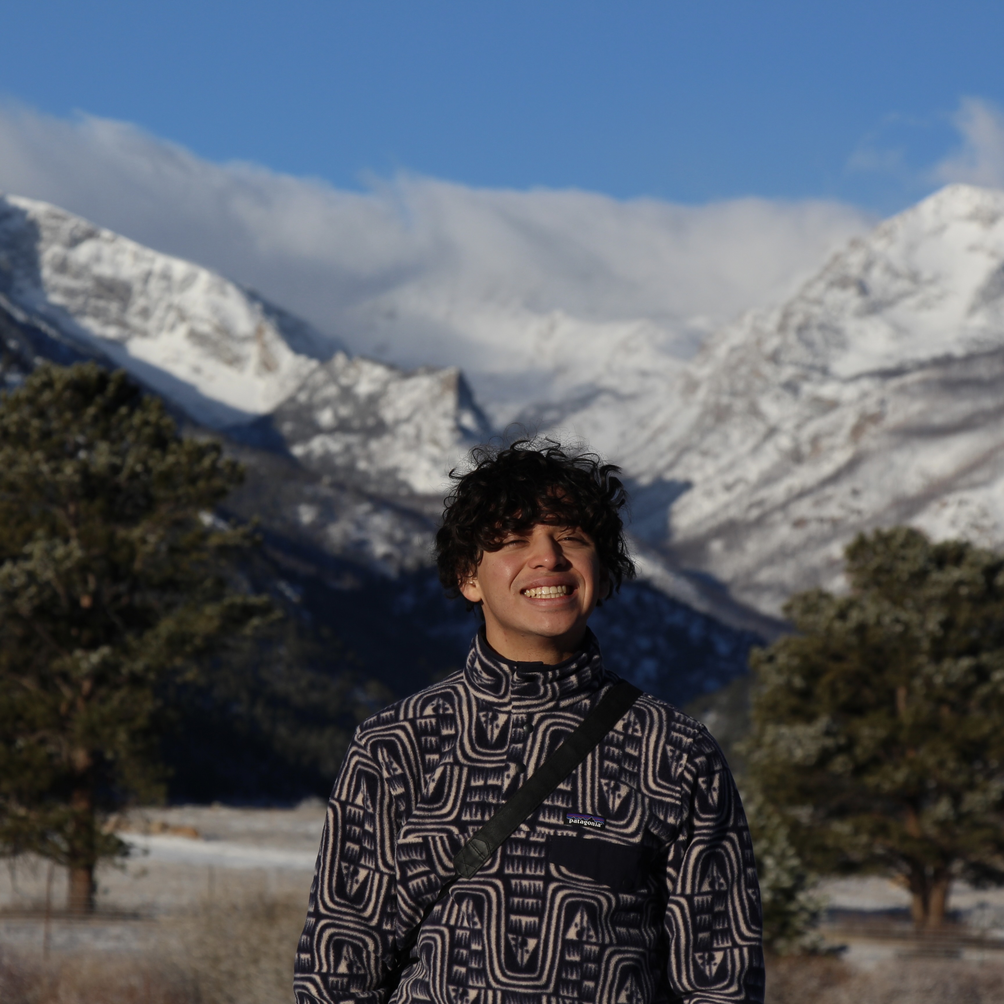 Kevin Menendez Mejia poses for the camera standing outside with mountains behind him