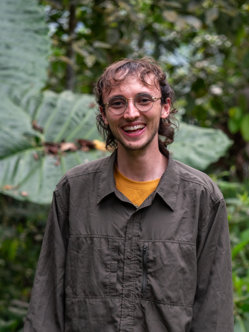 Zach Ginn stands smiling in a tropical rainforest in Ecuador