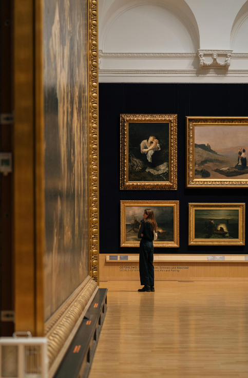 A patron looking at paintings in a museum.