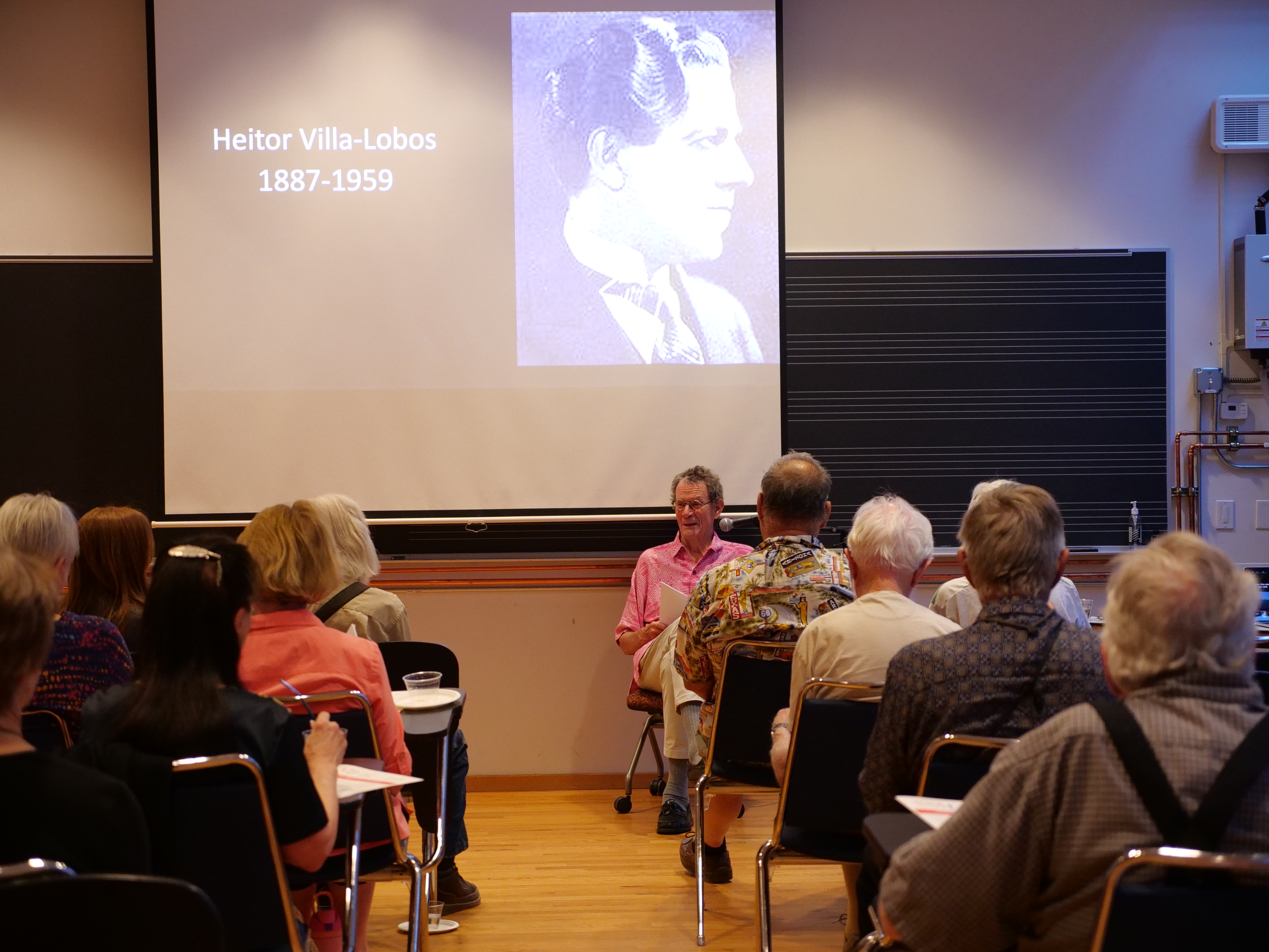 Michael Grace sits at the front of a classroom lecturing about Heitor Villa-Lobos in 2024.